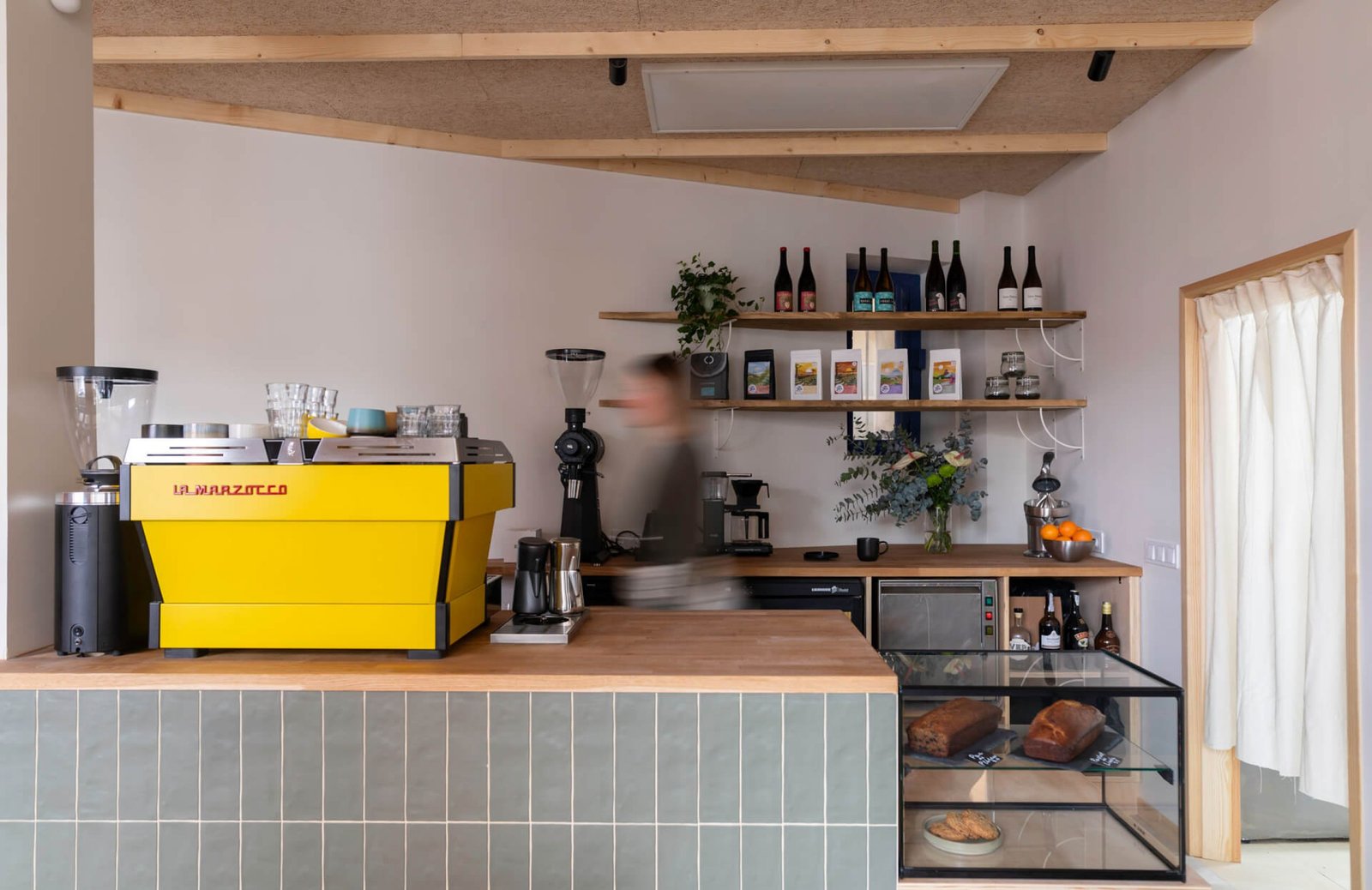 A yellow coffee machine in the corner of a small kitchen at La Gente Cafe, designed by TenZeroTwo Bureau
